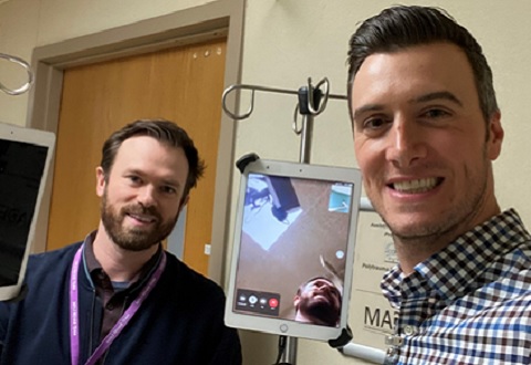 Ben Barrett, Physical Medicine and Rehabilitation Assistive Technology Program Coordinator and Beau Bedore, Spinal Cord Injury and Disorder Center Assistive Technology Director, standing next to one of the patient room mounted iPads.